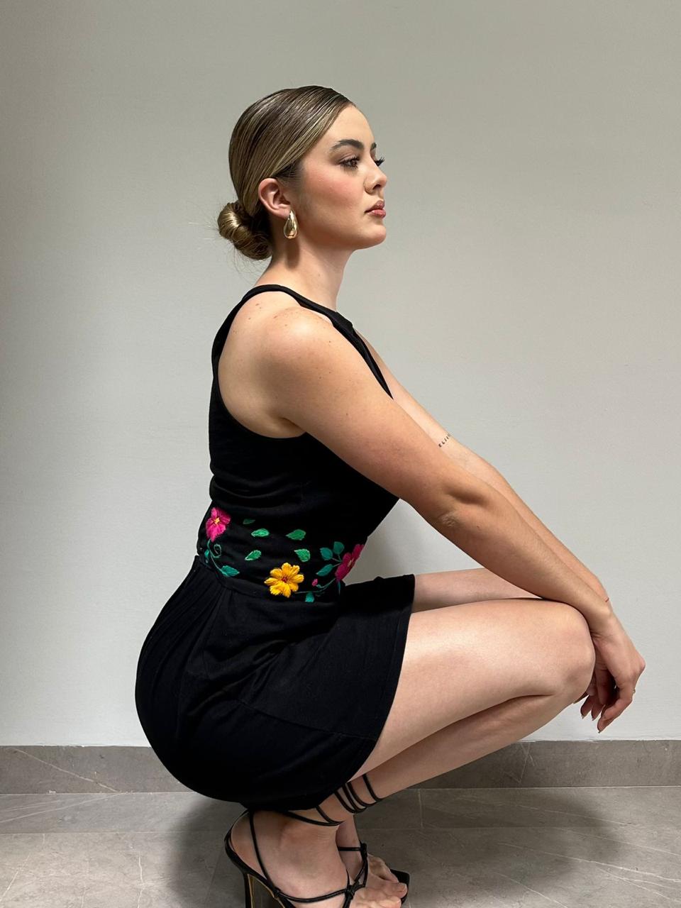 Detalle lateral de vestido negro con cinturilla floral bordada