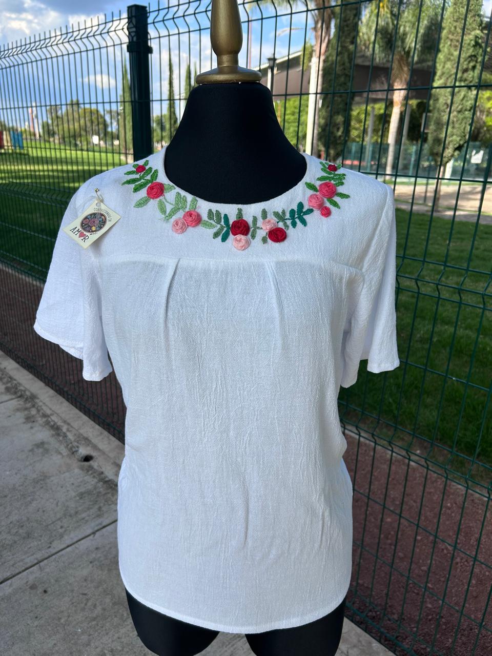 Blusa blanca con rosas rosadas y rojas bordadas alrededor del cuello