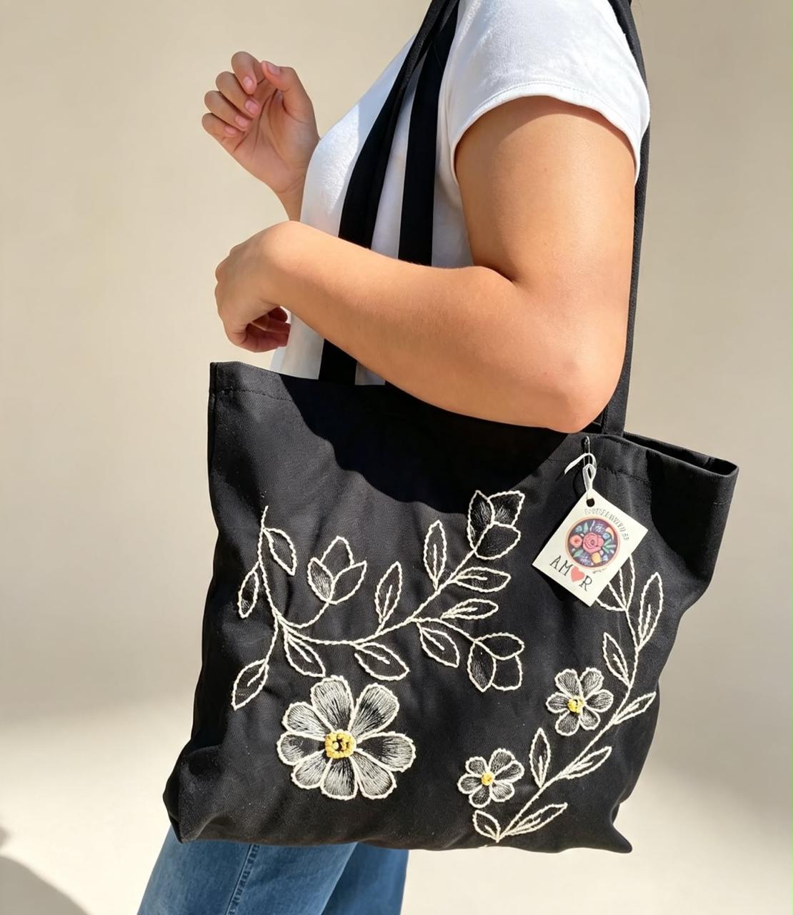 Bolsa negra con flores y ramas bordadas en hilo blanco